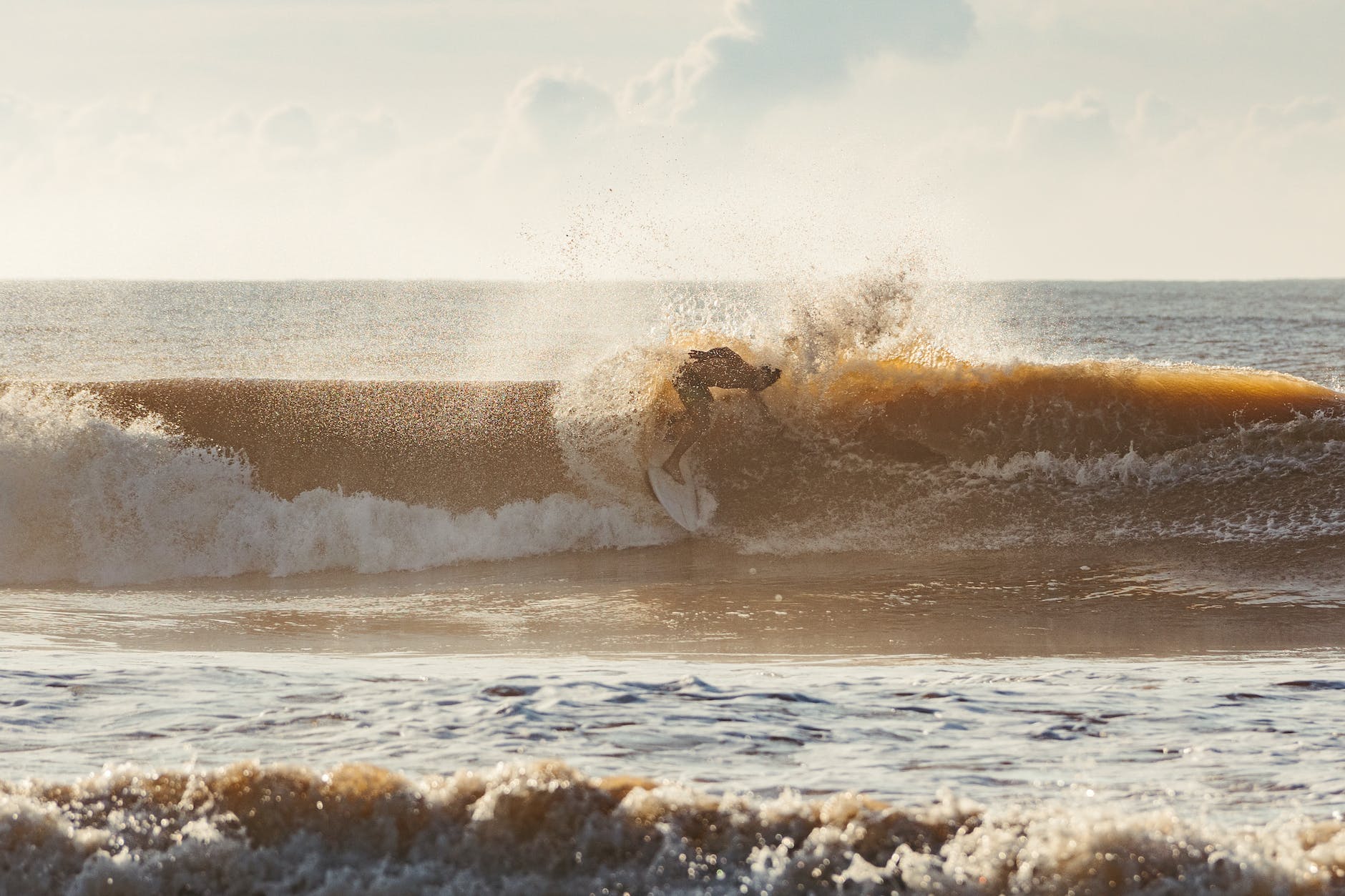man surfing atop wave by sea shore